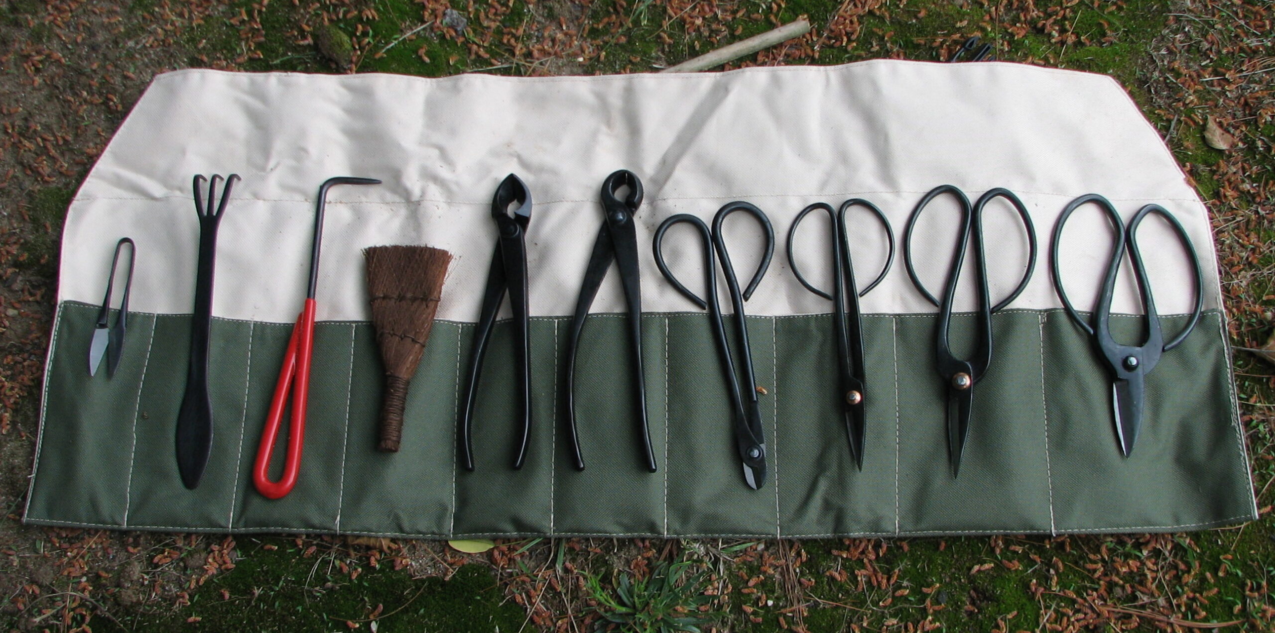 Roll-up bonsai tool set including a concave cutter, knob cutter, wire cutter, root hook, coir brush, and shears of several sizes