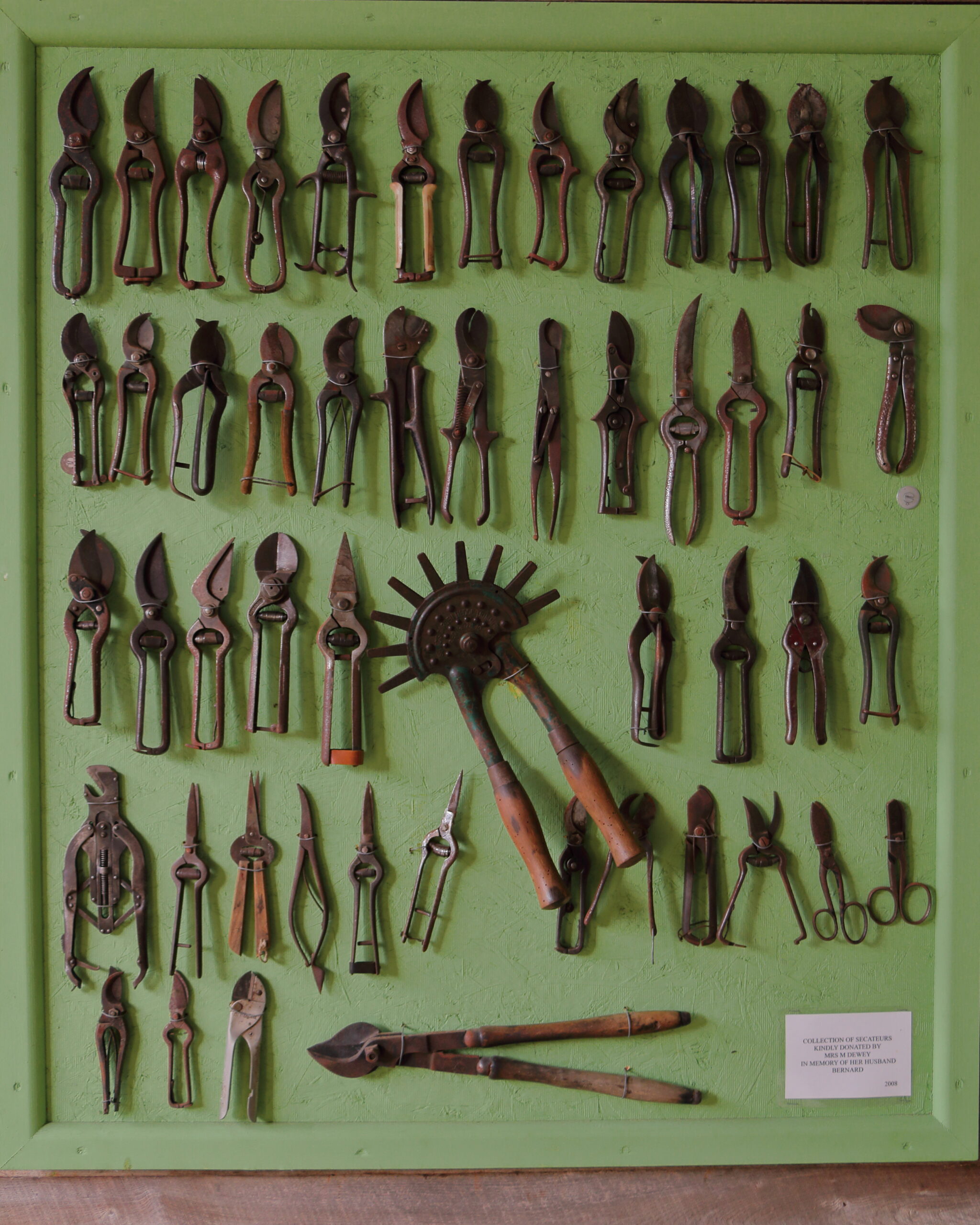 A wall-mounted display collection of various pruning secateurs hand pruners