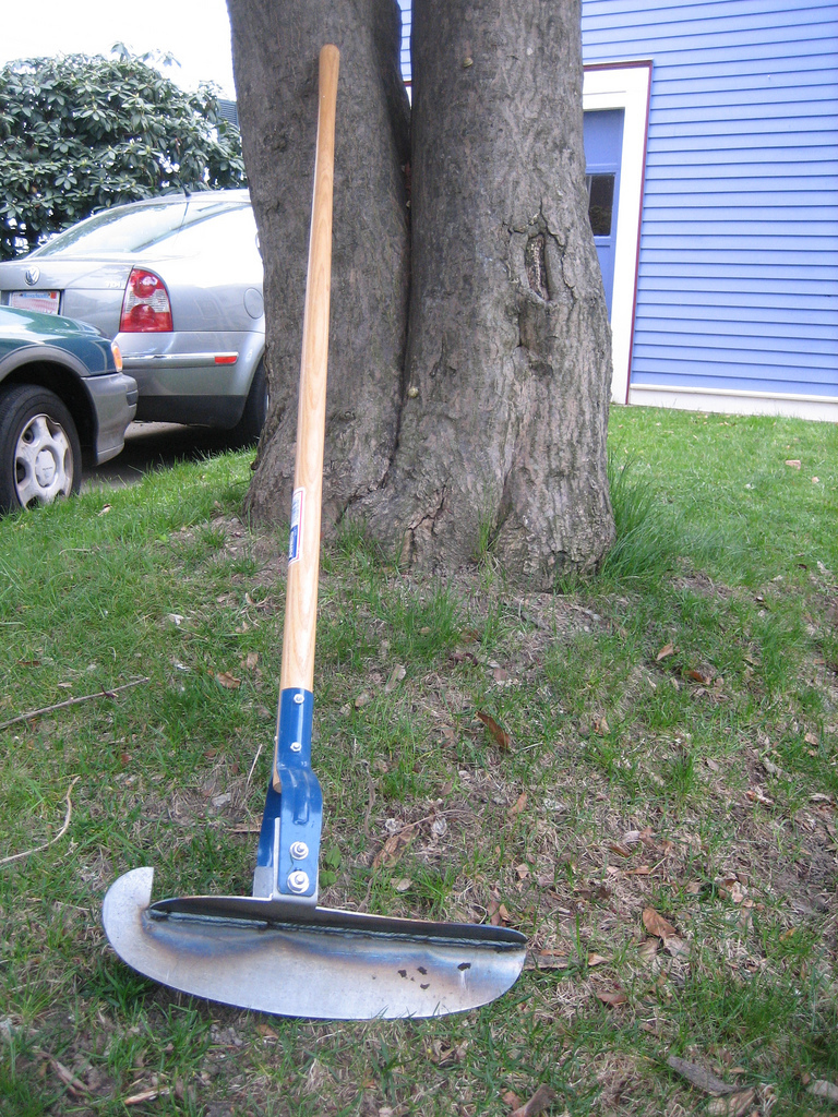 Manual half-moon edging tool used to cut clean lawn edges
